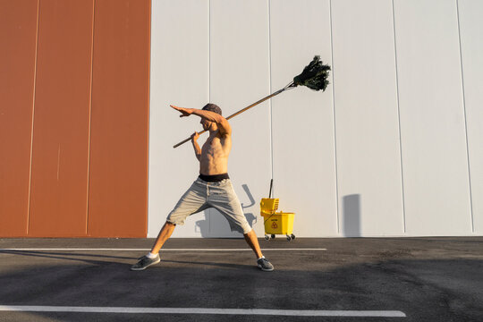 Acrobat playing with cleaning bucket and mop