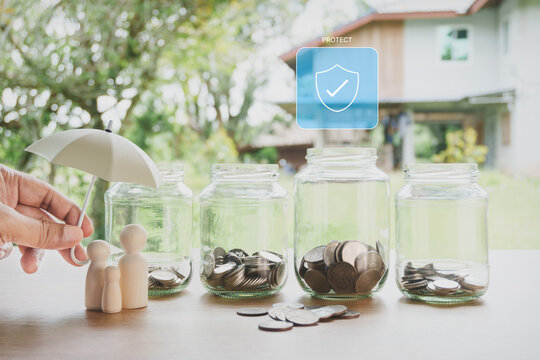 Emergency fund and financial protection concept with glass jars, family figurines, umbrella, savings coins and personal finance planning on wooden table with natural outdoor home background