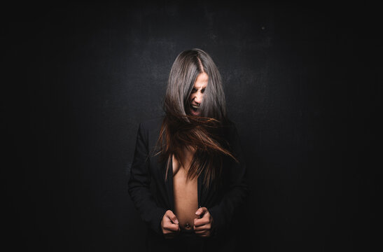 Young woman screaming and tossing in front of black background