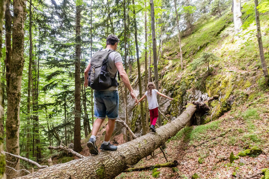 Father and daughter balancing on a log while hiking in the forest