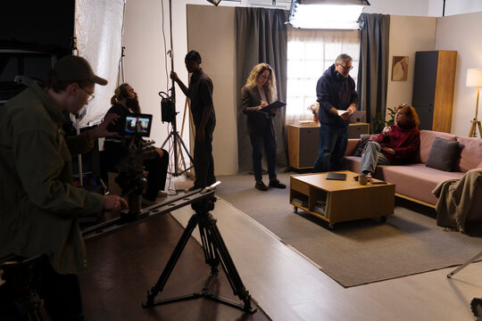 Film crew works with an actress on a living room studio set