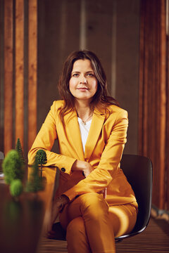 Portrait of businesswoman wearing yellow suit sitting at desk in office
