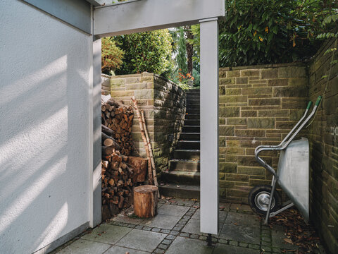 Wheelbarrow and firewood on a stone patio outside a villa