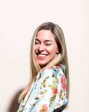 Smiling model in floral robe laughing indoors with copy space
