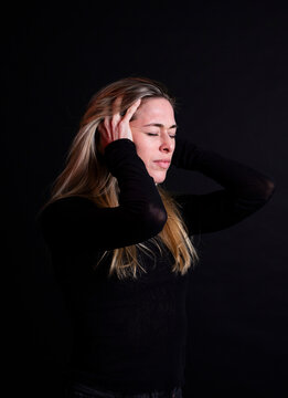 Holding head in hands experiencing stress against a black background