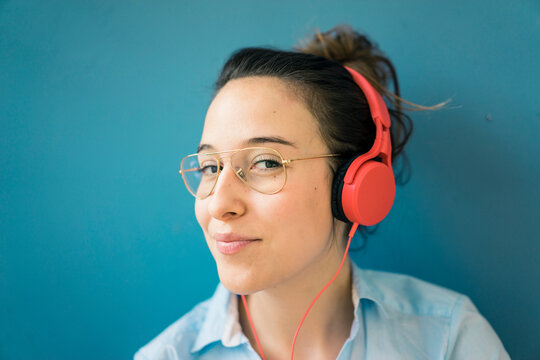 Portrait of smirking woman listening music with headphones