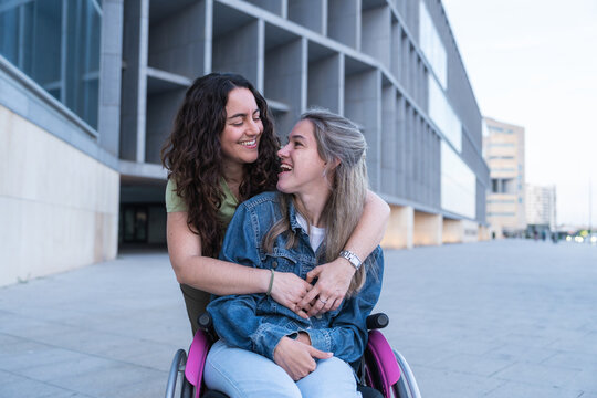 A woman hugs her friend in a wheelchair in the city