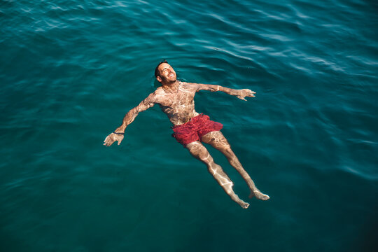 Carefree young man swimming in sea at vacation