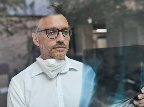 Portrait of radiologist behind windowpane looking at x-ray image