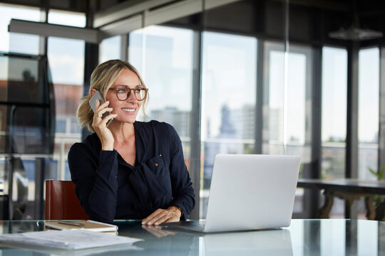 Businesswoman sitting in office, talking on the phone