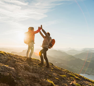 Austria, Salzkammergut, Cheering couple reaching mountain summit
