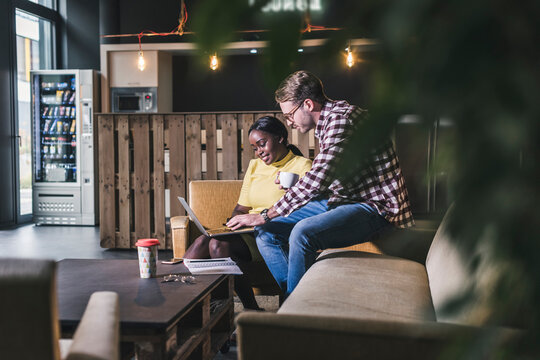 Colleagues working together on laptop in a cafe