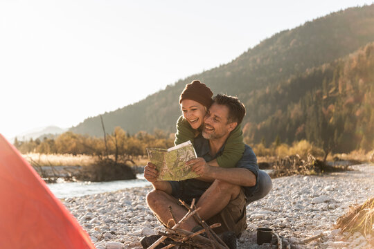 Mature couple camping at riverside, looking on map