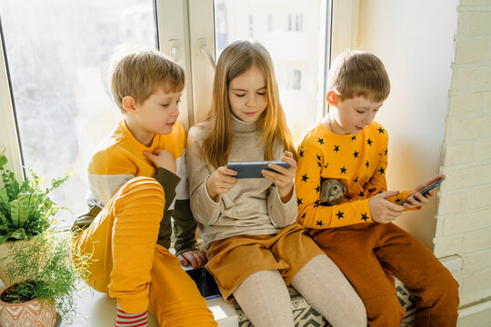 Happy boy with siblings using smart phone at home