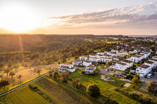Germany, Baden-Wurttemberg, Baltmannsweiler, Aerial view of sun setting over new development area in Schurwald