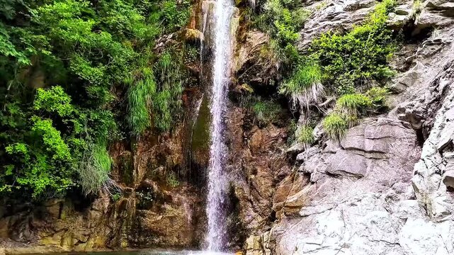 This waterfalls flow through a shaded woodland, where fresh mountain water and rugged rocks form a scenic waterfall landscape. Balta of Striga Waterfall, Edessa, Greece.