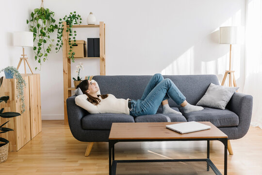 Woman lying down on sofa in living room
