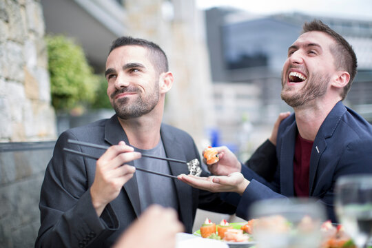 Gay couple eating sushi at outdoor restaurant