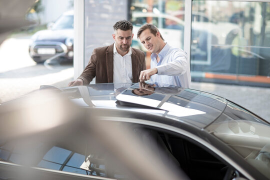 Car dealer talking to client at car dealership