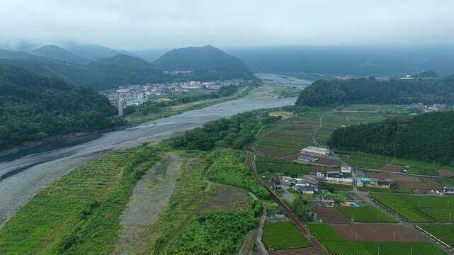 Aerial drone footage over river valley with morning mist in Shimada, Shizuoka, Japan