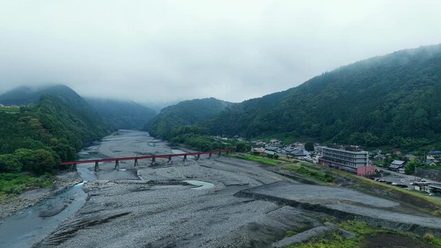 Aerial drone footage over Oi River and red bridge in Shimada, Shizuoka, Japan