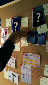 Investigator's hand placing an unsolved sticky note on a cork evidence board with photos, clues, and red thread connecting suspects and proof in a police station during a complex investigation