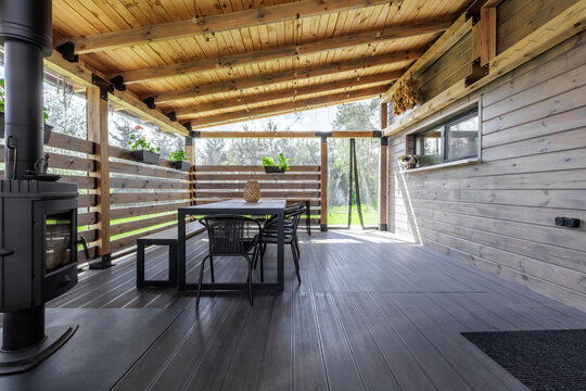Modern Covered Wooden Terrace Interior with Stove and Dining Set