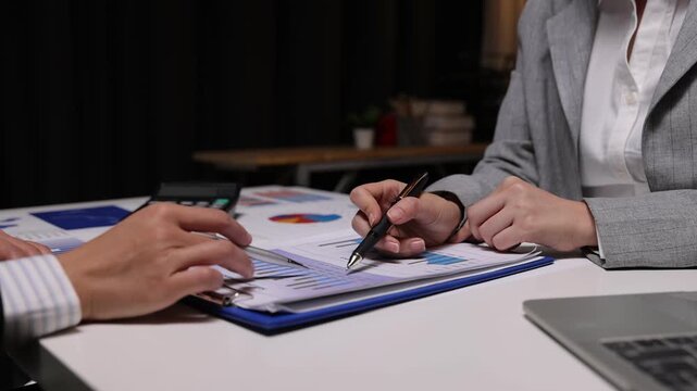 Close-up of professional analysts examining documents with charts. Business people planning strategy and analyzing market research data in an office meeting.