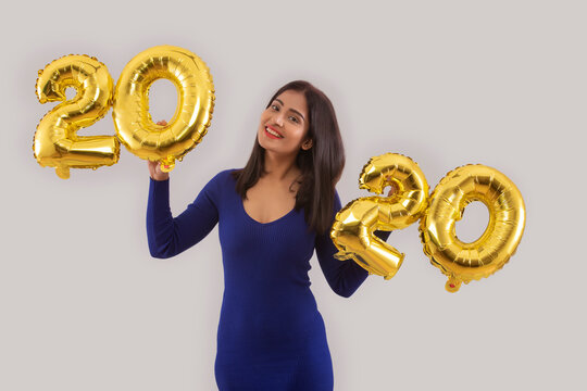 Young woman holding 2020 golden balloons during a new year party. 