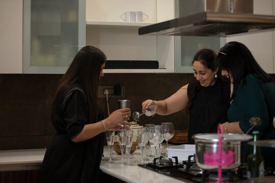 Friends sharing a light moment while pouring drinks at a party.
