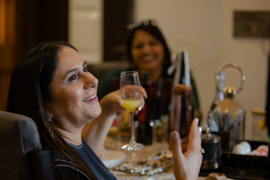 Woman telling a story while having a drink at a Kitty party. 