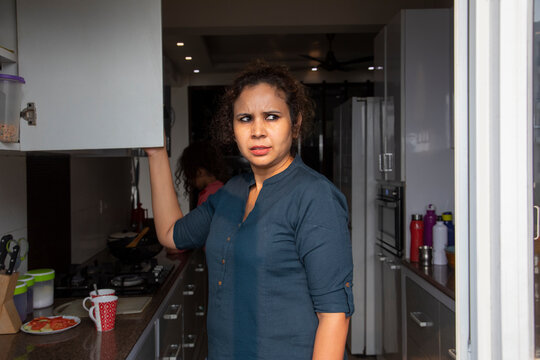 Woman suspiciously looking outside the window at home. 