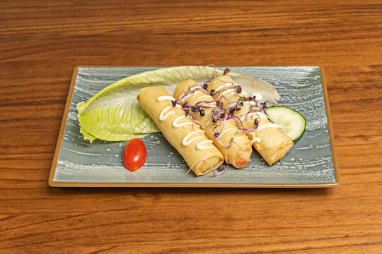 Fried Cheese Rolls Drizzled With Sauce and Sprouts on Rectangular Ceramic Plate