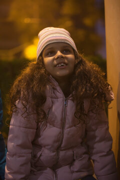 Young girl wearing a beanie looking up at the sky. (Children)