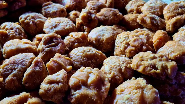 A close-up of traditional jaggery chunks highlights rich golden-brown colour and naturally uneven texture. Rustic appearance emphasises traditional food preparation and craftsmanship.