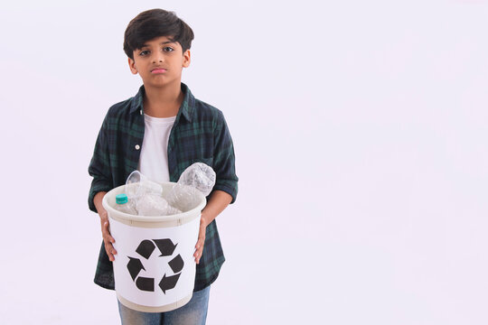 Young boy holding a recycling bin with plastic bottles. (Children) 