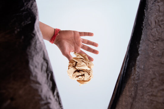 Person throwing waste inside a garbage bag. (Children)