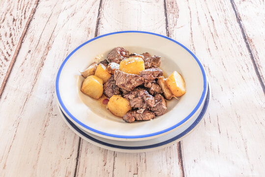 "Grilled Sirloin Beef Cubes with Roasted Baby Potatoes and Garlic on Blue-Rimmed Plate"