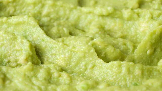 Person using a knife to texturize fresh homemade avocado puree, side view.