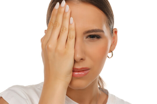 Half face portrait of woman covering one eye, eye exam concept, direct gaze, on white background