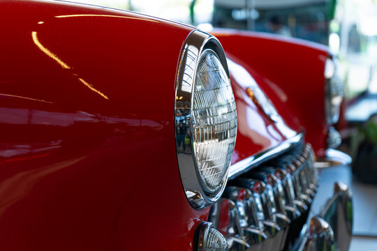 Side angle close up of chrome grille and headlight on classic red car