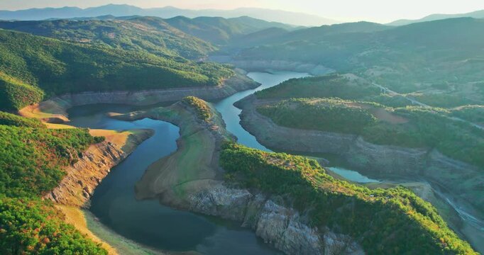 Aerial view of a drought-stricken dam lake at sunset, revealing dry riverbed