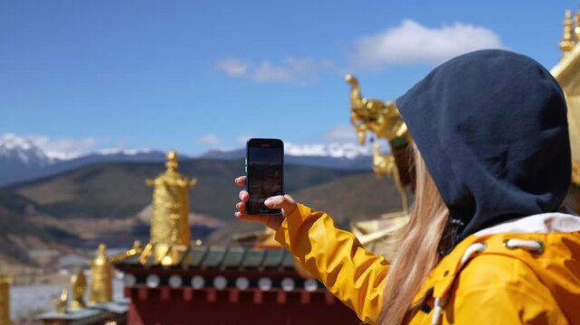 Young Woman Traveller shoots with a phone the Songzanlin Lamasery in Shangri-la, Yunnan, China. Famous Tibetan Monastery