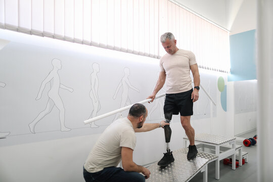 Rehabilitation specialist assists to amputee veteran during rehabilitation exercises