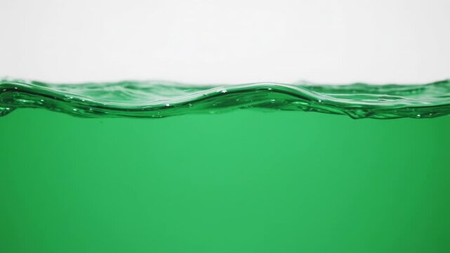 Green liquid waves with subtle ripples during a clean studio shot against a bright backdrop