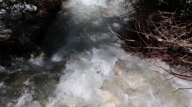 Video of the raging Sairam Su mountain river in Kazakhstan. Powerful fast-flowing stream with splashing white water rushing past rocks in scenic wild nature.
