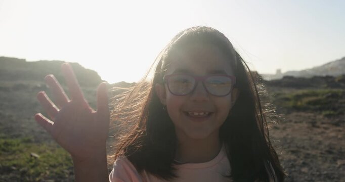 Happy young female child greeting and waving hands on camera outdoor - Youth, childhood and UGC content