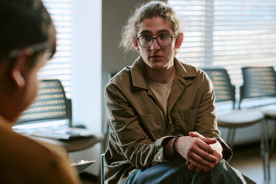Young adult man participating in support group therapy session, listening and sharing during counseling meeting. Ideal for mental health, recovery, counseling, wellness campaigns