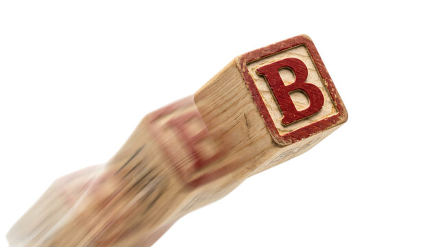 Vintage wooden alphabet block with letter B in motion, falling toy cube with motion blur, classic nursery play block on white background