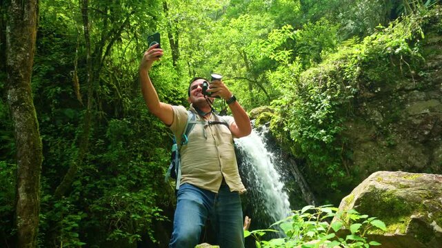 Adventurous man taking selfie near a beautiful waterfall